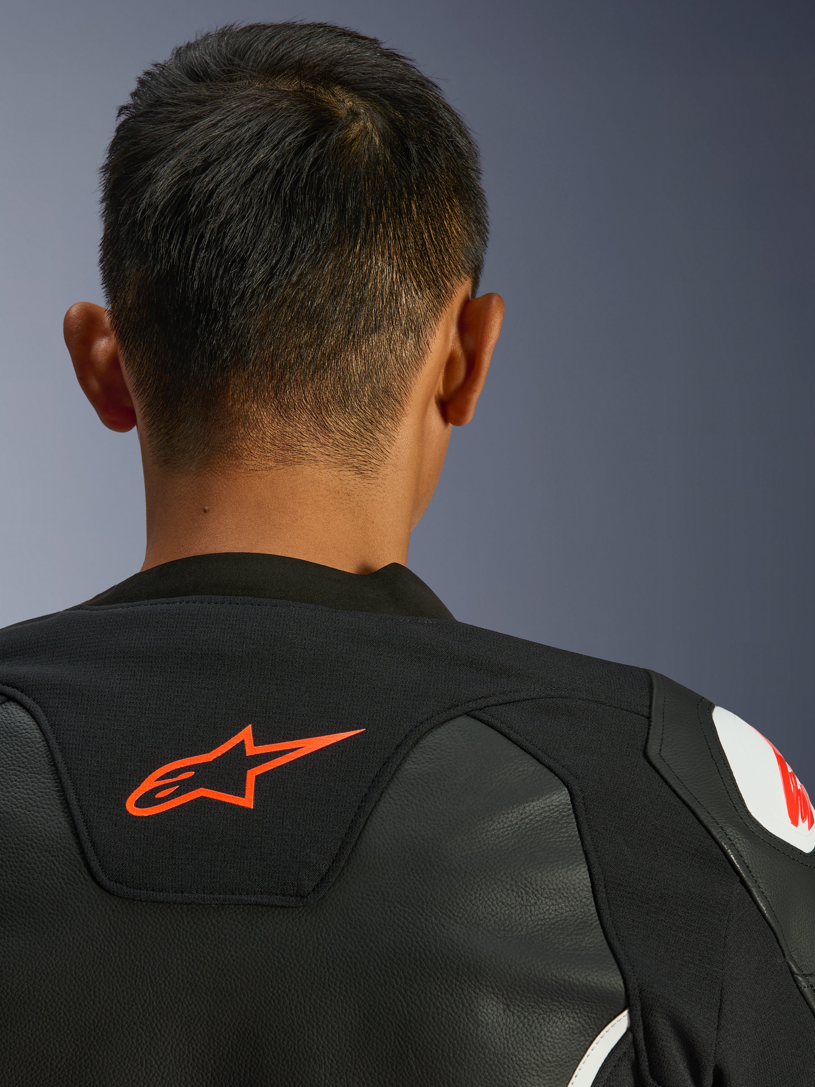 Alpinestars GP Force V2 Leather Jacket, nero e bianco, vista ravvicinata posteriore di collo e spalle, logo Alpinestars rosso, pelle premium con pannelli elasticizzati in tessuto, design sportivo ad alte prestazioni