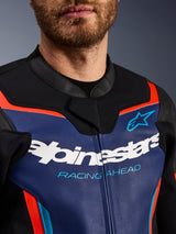 Giacca in pelle Alpinestars GP Force V2, vista dettagliata di petto e colletto, blu, nero e rosso fluo, con logo Alpinestars bianco e scritta 'RACING AHEAD' azzurra, texture in pelle premium con accenti fluorescenti