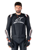 Giacca in pelle Alpinestars Missile V3 Ignition, nero con accenti bianchi e rossi, indossata da un modello con guanti e pantaloni da corsa coordinati, giacca da moto sportiva derivata dalla MotoGP con branding evidente