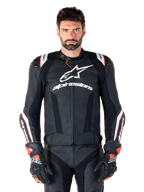 Giacca in pelle Alpinestars Missile V3 Ignition, nero con accenti bianchi e rossi, indossata da un modello con guanti e pantaloni da corsa coordinati, giacca da moto sportiva derivata dalla MotoGP con branding evidente