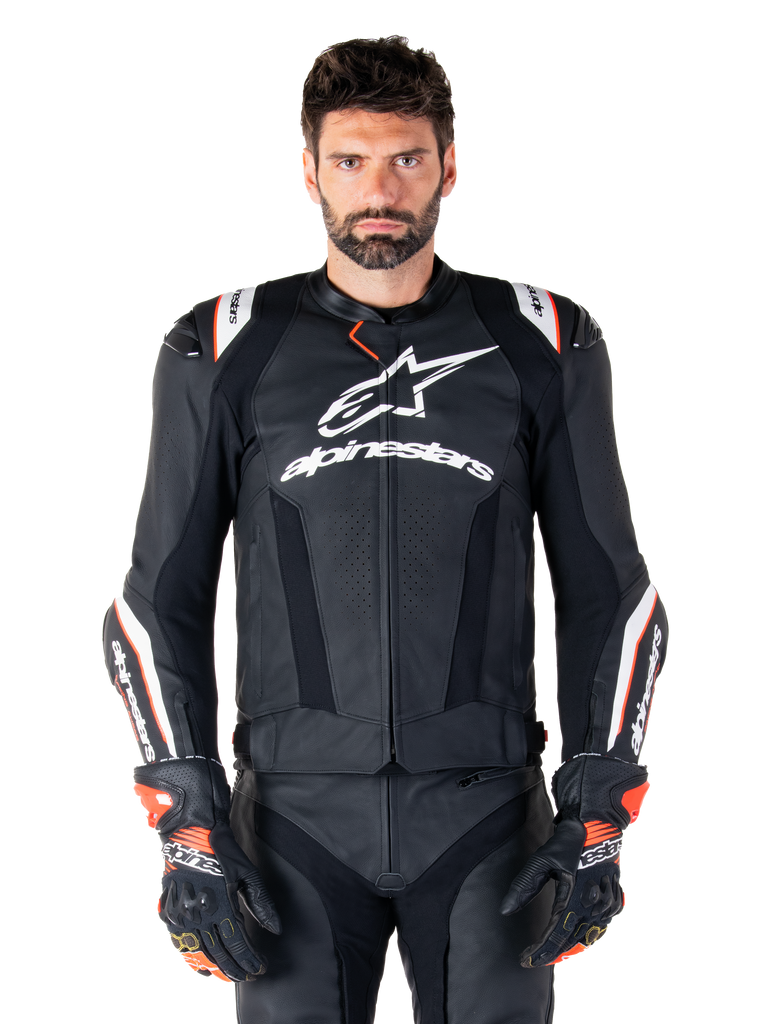 Giacca in pelle Alpinestars Missile V3 Ignition, nero con accenti bianchi e rossi, indossata da un modello con guanti e pantaloni da corsa coordinati, giacca da moto sportiva derivata dalla MotoGP con branding evidente