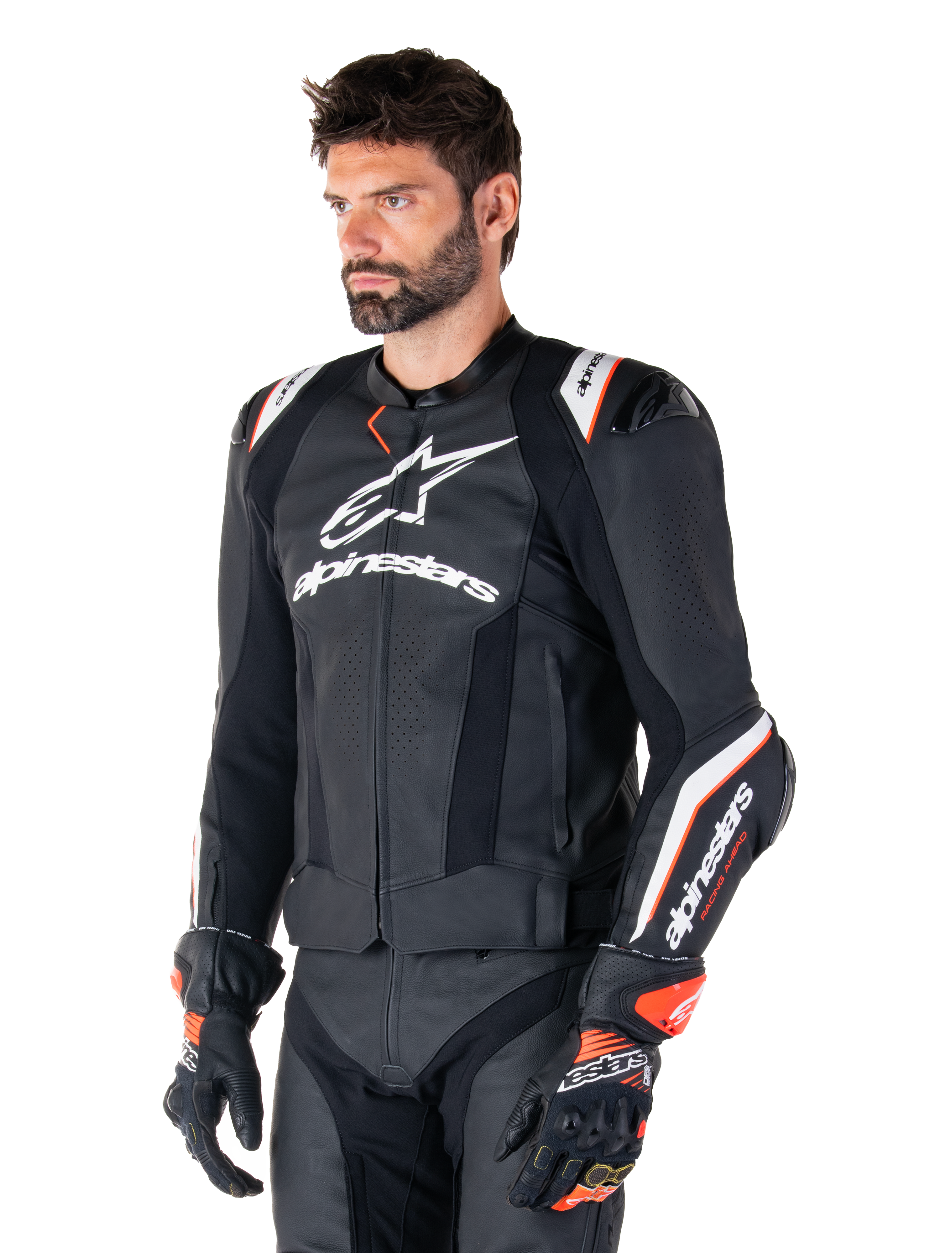 Modello uomo che indossa la giacca in pelle Alpinestars Missile V3 Ignition, nero con accenti bianchi e arancioni, caratterizzata da loghi bianchi evidenti, sezioni in pelle traforata e protezioni sulle spalle, abbinata a guanti da corsa per un look sportivo da gara.