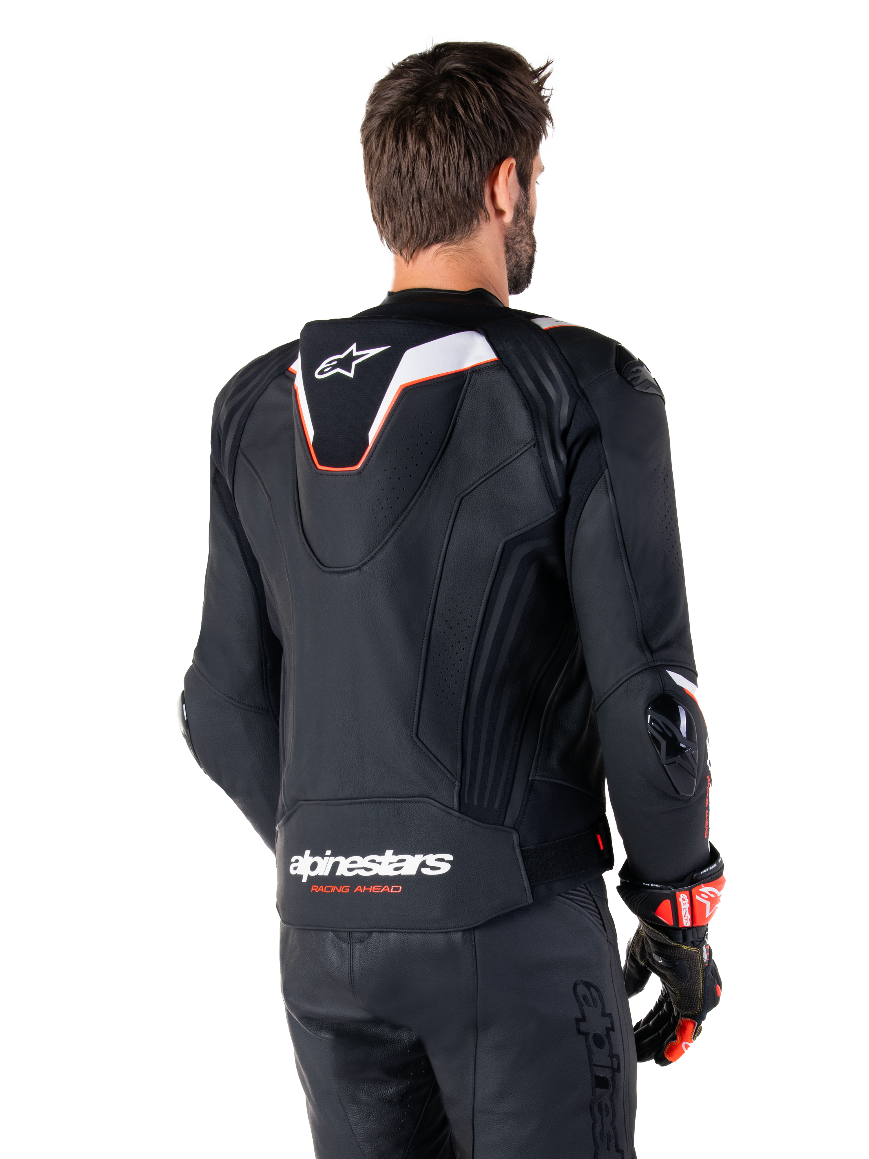 Giacca in pelle Alpinestars Missile V3 Ignition, vista posteriore, nero con accenti bianchi e rossi, con gobba aerodinamica sportiva sottile e marchio Alpinestars, indossata con pantaloni in pelle coordinati e guanti da corsa