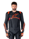 Giacca in pelle Alpinestars Missile V3 Ignition, giacca da moto racing, nero e rosso fluo, indossata con guanti da corsa e pantaloni in pelle coordinati, con ventilazione traforata e logo Alpinestars in evidenza, abbigliamento da corsa professionale