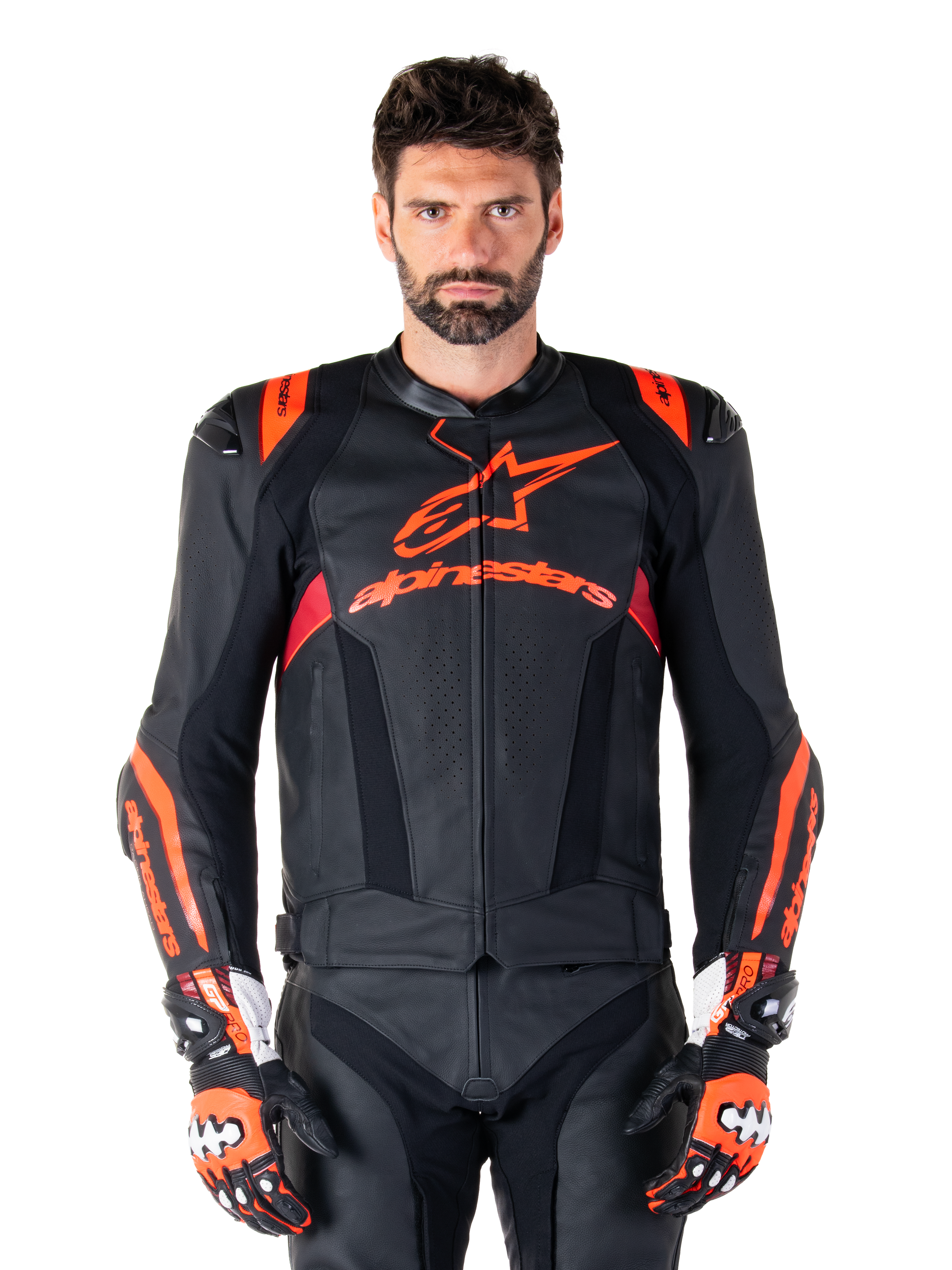 Giacca in pelle Alpinestars Missile V3 Ignition, giacca da moto racing, nero e rosso fluo, indossata con guanti da corsa e pantaloni in pelle coordinati, con ventilazione traforata e logo Alpinestars in evidenza, abbigliamento da corsa professionale