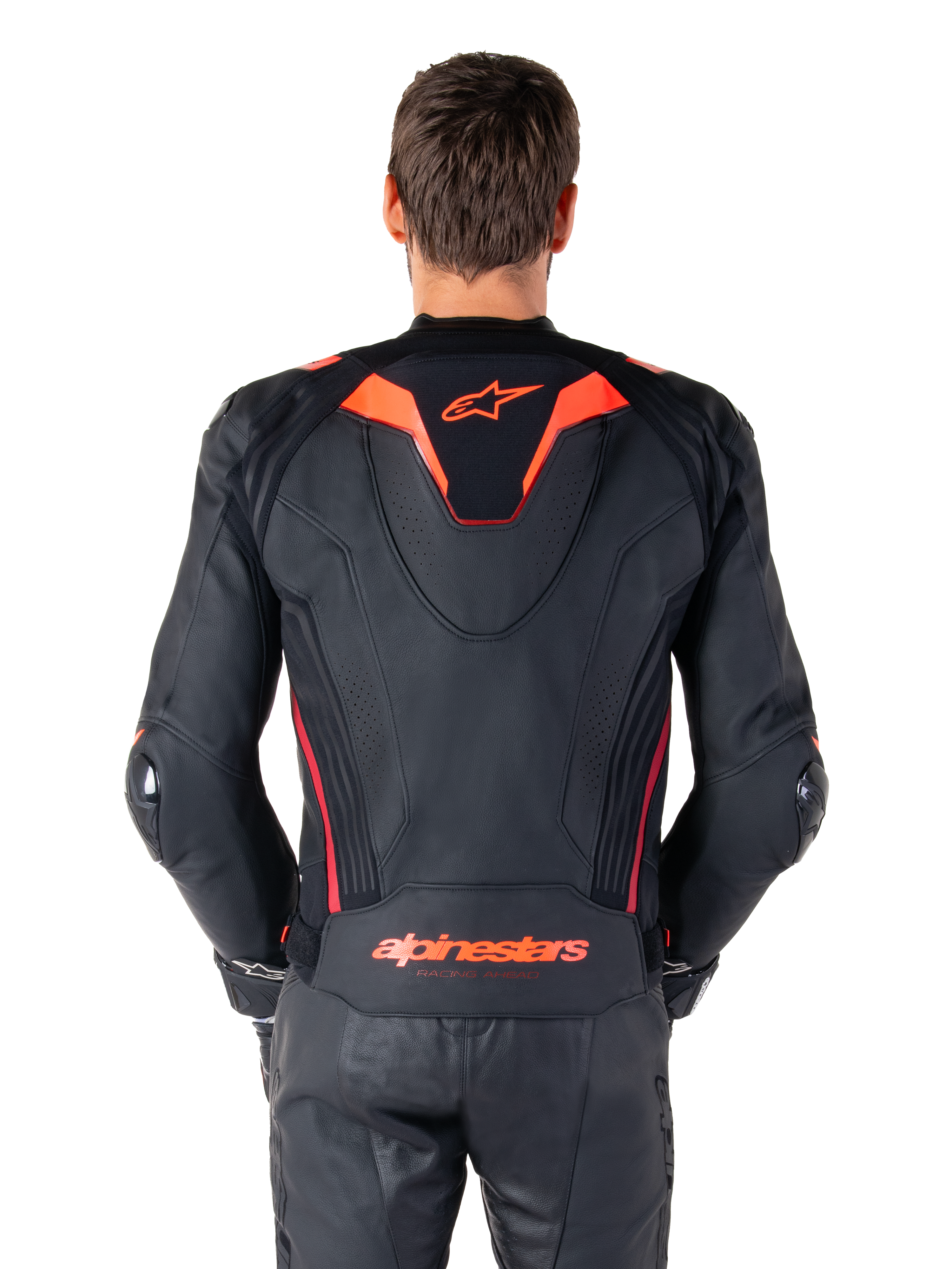 Giacca in pelle Alpinestars Missile V3 Ignition, vista posteriore, nero con accenti rosso fluo e rosso scuro, con gobba aerodinamica sportiva e logo Alpinestars sulla schiena, indossata con pantaloni coordinati in pelle nera, abbigliamento tecnico da competizione motociclistica