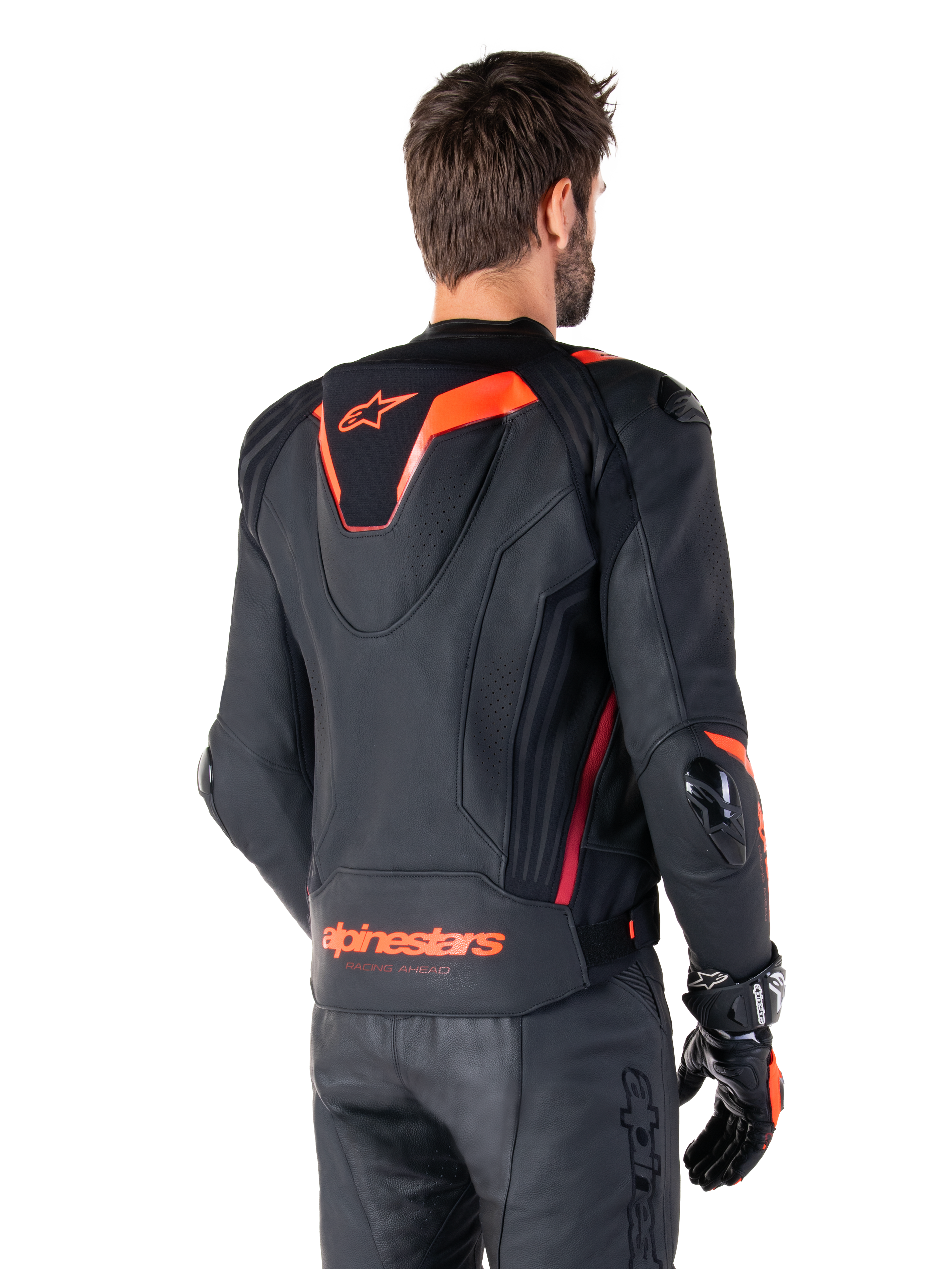 Giacca in pelle Alpinestars Missile V3 Ignition, giacca sportiva da corsa da uomo, nero con dettagli rosso fluo, vista posteriore con la sottile gobba sportiva aerodinamica e marchio Alpinestars sulla parte bassa della schiena, indossata con pantaloni in pelle neri e guanti da corsa, design motorsport professionale ed elegante
