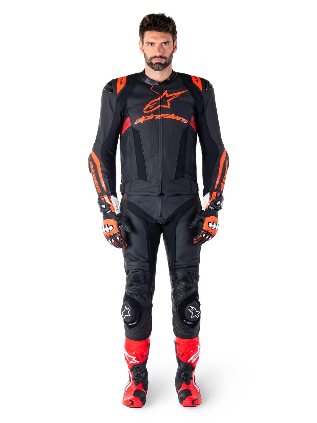 Modello maschile che indossa la giacca in pelle Alpinestars Missile V3 Ignition in Nero Rosso Fluo Rosso Scuro, equipaggiamento completo da gara motociclistica con pantaloni in pelle coordinati, guanti da corsa e stivali, caratterizzato dal logo Alpinestars sul petto, posa frontale, abbigliamento professionale per guida sportiva