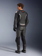 Giacca in pelle Alpinestars GP Force V2 Air, nero e bianco, vista posteriore su modello con pannello posteriore traforato per la ventilazione, branding bianco e logo a stella rosso, indossata con pantaloni da corsa in pelle abbinati, guanti e stivali