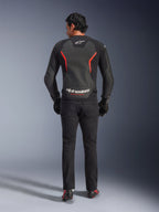 Giacca in pelle Alpinestars GP Force V2 Air, nero e rosso fluo, vista posteriore su modello, con pannelli in pelle traforata sul retro, accenti rossi e logo Alpinestars, abbinata a jeans da moto neri e guanti per un look sportivo.