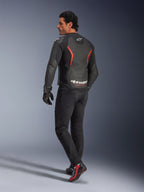 Modello visto da dietro che indossa la giacca in pelle Alpinestars GP Force V2 Air in Black Red Fluo, con ampie perforazioni sulla schiena e logo bianco, abbinata a jeans da moto neri, guanti e stivali da moto neri e rossi in un contesto da studio.