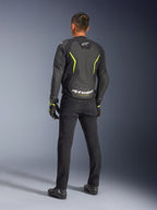 Giacca in pelle Alpinestars GP Force V2 Air, nero e giallo fluo, vista posteriore di un pilota che indossa la giacca in pelle traforata, con accenti gialli angolari, logo Alpinestars bianco e scritta 'RACING AHEAD' sulla parte bassa della schiena, abbinata a pantaloni e stivali da moto neri.