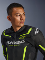 Giacca in pelle Alpinestars GP Force V2 Air, nero e giallo fluo, giacca da moto sportiva traforata con logo bianco sul petto e scritta 'Racing Ahead', accenti neon e slider protettivi sulle spalle, indossata da un modello uomo.