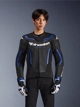 Giacca in pelle Alpinestars GP Force V2 Airflow, Nero Blu Metallizzato, giacca da moto con pelle traforata e dettagli blu, indossata da un modello con guanti da corsa coordinati e pantaloni neri, abbigliamento tecnico sportivo professionale