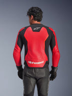 Giacca in pelle Alpinestars GP Force V2 Air in rosso e nero, vista posteriore che mostra la struttura in pelle traforata per la ventilazione, marchio Alpinestars bianco sulla parte inferiore della schiena e pannelli elasticizzati integrati, indossata con pantaloni e guanti da moto in pelle nera.