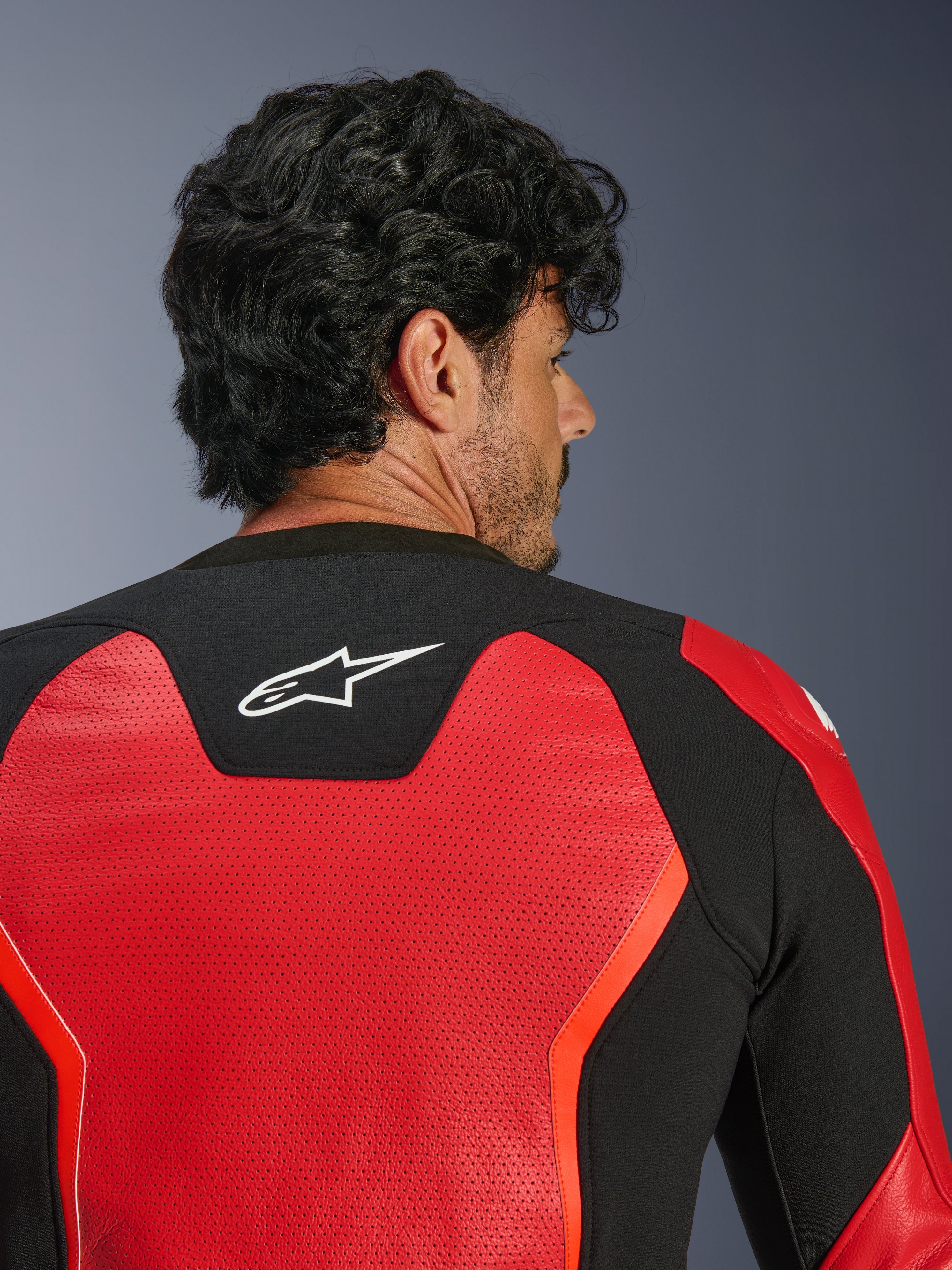 Alpinestars GP Force V2 Air Leather Jacket, rossa e nera, vista ravvicinata posteriore con pelle ampiamente traforata per il flusso d'aria, pannello elasticizzato nero con logo Astars bianco, giacca da moto con vestibilità sportiva