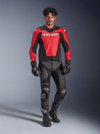 Giacca in pelle Alpinestars GP Force V2 Air, rosso e nero, pelle traforata con loghi bianchi, indossata da un modello con pantaloni racing e guanti in pelle nera, abbigliamento professionale da moto