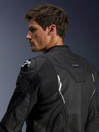 Giacca in pelle Alpinestars Dusk, nera con accenti bianchi, vista posteriore su modello, con protezioni per le spalle DFS e logo Alpinestars, pannelli a soffietto in pelle elasticizzata per la mobilità e marchio 'DUSK' sulla parte superiore della schiena, giacca da moto in pelle bovina premium per guida su strada e sportiva.