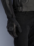 Alpinestars Giacca in pelle GP Plus V4, giacca da moto sportiva, nero, vista dettagliata della regolazione in vita e della cerniera sulla manica, indossata con guanti da moto neri, abbigliamento tecnico professionale dallo stile moderno