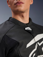 Giacca in pelle Alpinestars GP Plus V4, giacca da moto sportiva, nero e bianco, primo piano del colletto in pelle testurizzata e della linguetta con logo Alpinestars, grafica bianca sul petto, design di derivazione racing