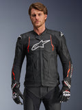 Alpinestars Dusk Airflow Leather Jacket, giacca racing in pelle nera con accenti rosso fluo e bianchi, dotata di ampie perforazioni per la ventilazione, logo bianco sul petto e slider esterni sulle spalle, indossata da un modello con guanti racing coordinati