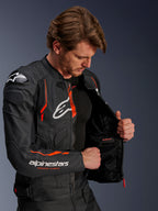 Giacca in pelle Alpinestars Dusk Airflow, nero e rosso fluo, indossata da un motociclista, parzialmente aperta per mostrare la fodera interna in rete e la tasca impermeabile, con pelle traforata per la ventilazione e loghi evidenti sul petto e sul braccio.