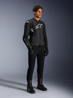 Alpinestars Dusk Airflow Leather Jacket, nero e bianco, indossata con pantaloni da moto, guanti e stivali neri, con pannelli in pelle traforata e loghi bianchi, stile racing sportivo.