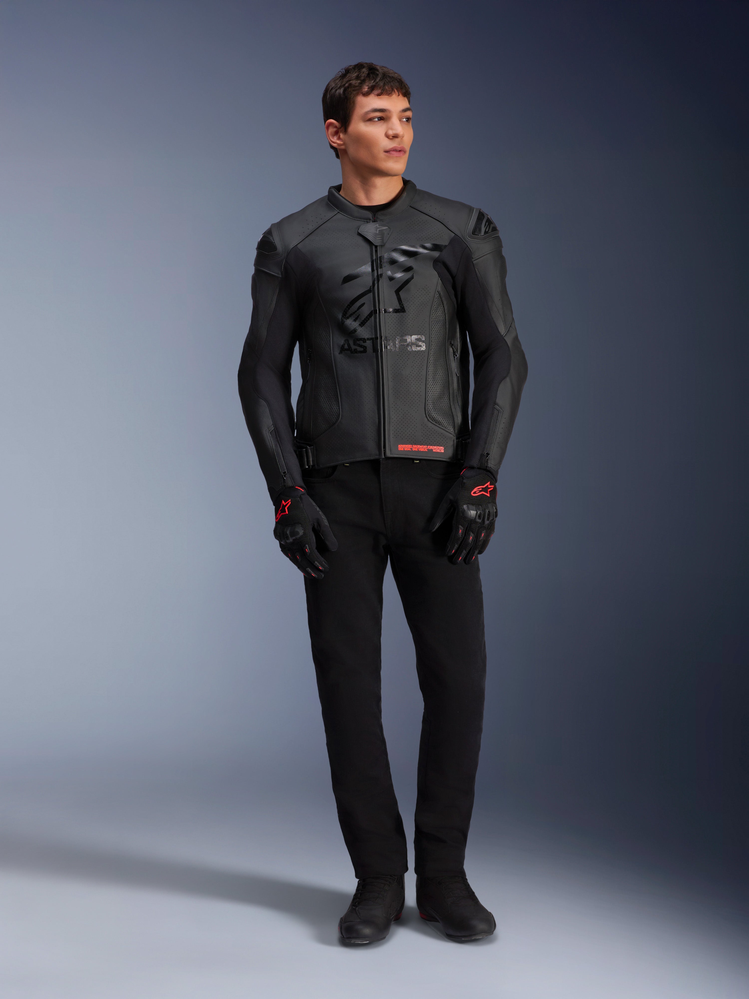 Giacca in pelle Alpinestars GP Plus R V4 Airflow, nero, indossata da un modello con guanti e pantaloni neri coordinati, caratterizzata da pannelli in pelle traforata, grande logo a stella in tono sul petto e vestibilità sportiva.