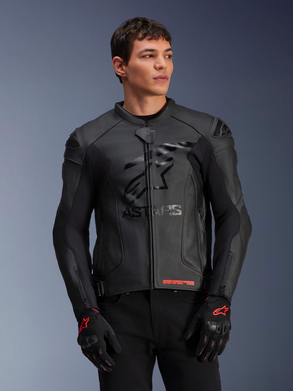 Alpinestars GP Plus R V4 Airflow Leather Jacket, giacca da moto racing in pelle nera con costruzione in pelle traforata, logo ASTARS sul petto e protezioni per le spalle DFS, indossata con guanti neri e rossi