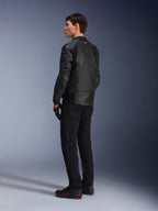 Giacca in pelle Alpinestars GP Plus R V4 Airflow, giacca da moto sportiva da uomo, completamente nera, vista posteriore a tre quarti su un modello, con pannelli in pelle traforata, logo rosso sul retro e protezioni integrate sulle spalle, indossata con pantaloni neri e scarpe da guida