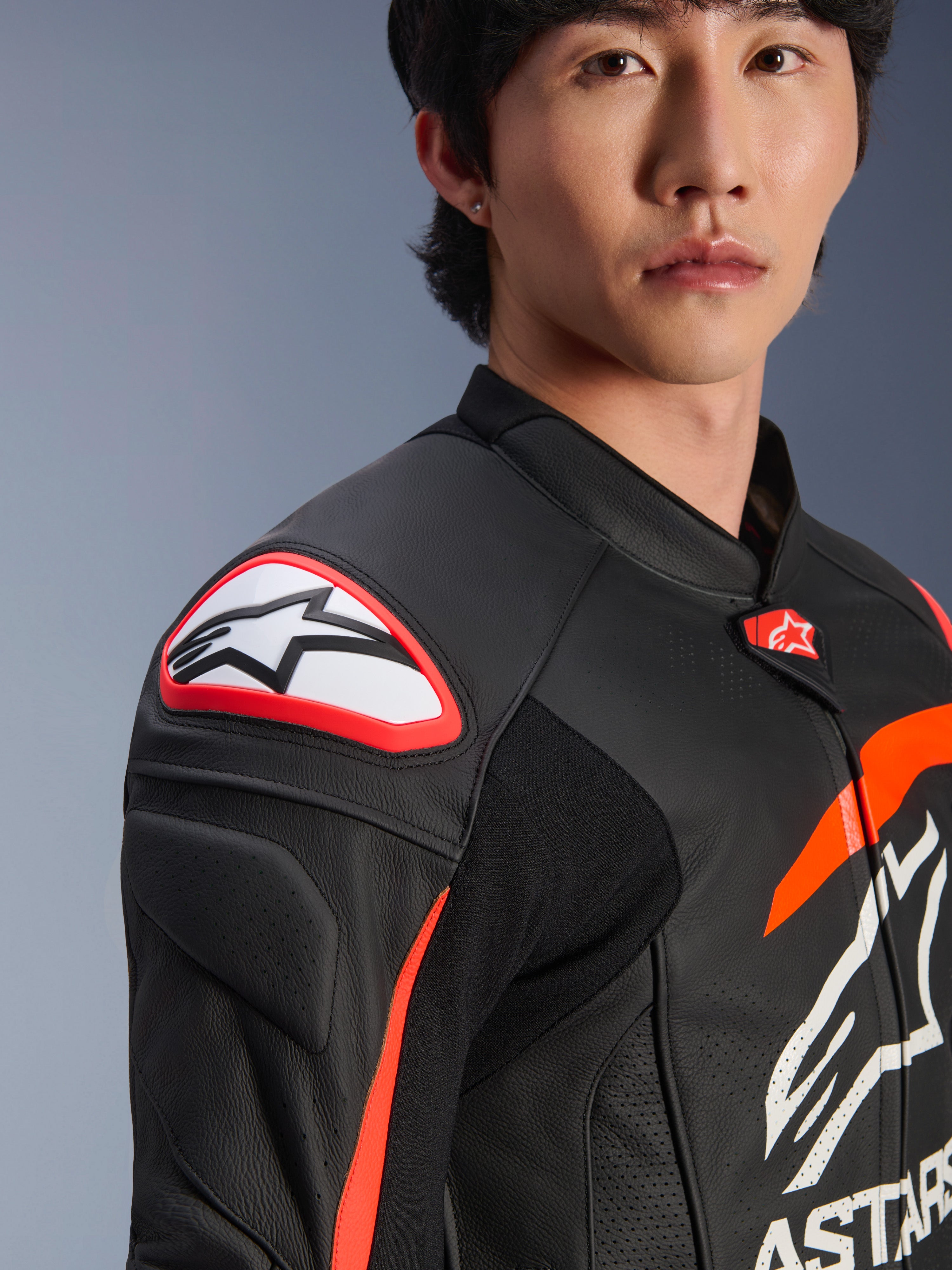 Giacca in pelle Alpinestars GP Plus R V4 Airflow, Nero Rosso Fluo Bianco, primo piano del modello che indossa la giacca, con logo Astar in evidenza sullo slider della spalla e petto in pelle traforata per il massimo flusso d'aria, abbigliamento professionale da motorsport