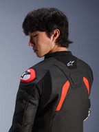 Giacca in pelle Alpinestars GP Plus R V4 Airflow, nero con dettagli rosso fluo e bianchi, vista ravvicinata della schiena e della spalla su un modello, con zone in pelle traforata, logo Alpinestars e protezione integrata sulla spalla per prestazioni motociclistiche.