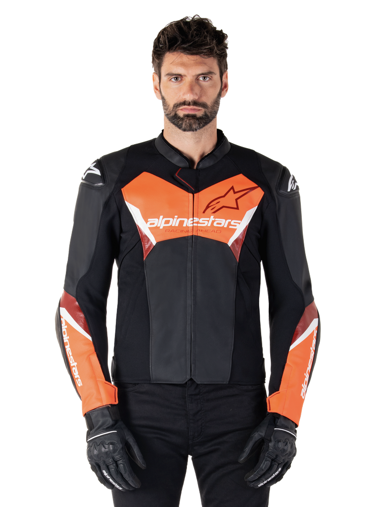 Giacca in pelle Alpinestars Faster V3, giacca da moto sportiva, nero e rosso fluo, indossata da un modello uomo con guanti e pantaloni da moto neri, con logo Alpinestars su petto e avambracci, realizzata in pelle premium per la guida su strada.