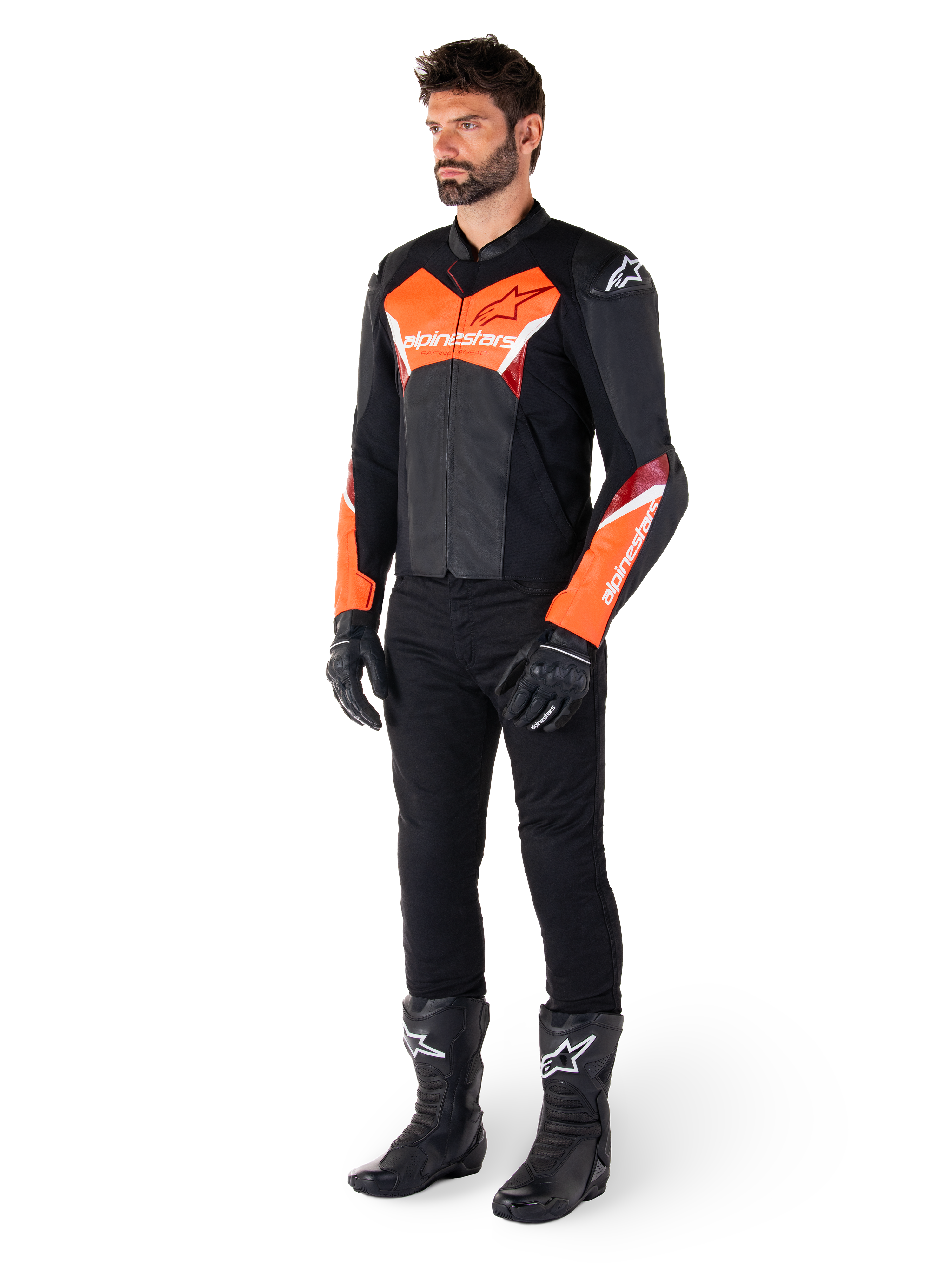 Motociclista che indossa la giacca in pelle Alpinestars Faster V3 in nero e rosso fluo, abbinata a pantaloni da moto, guanti e stivali neri. La giacca presenta una silhouette di derivazione racing con audaci accenti rosso fluorescente su petto e maniche, marchio Alpinestars bianco e una struttura in pelle premium.