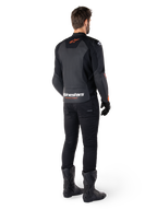 Giacca in pelle Alpinestars Faster V3, giacca da moto sportiva, nero e rosso fluo, vista posteriore indossata con pantaloni neri e stivali neri, con scritta 'alpinestars RACING AHEAD' sulla parte inferiore della schiena e un piccolo logo a stella rosso, struttura in pelle dal taglio sportivo