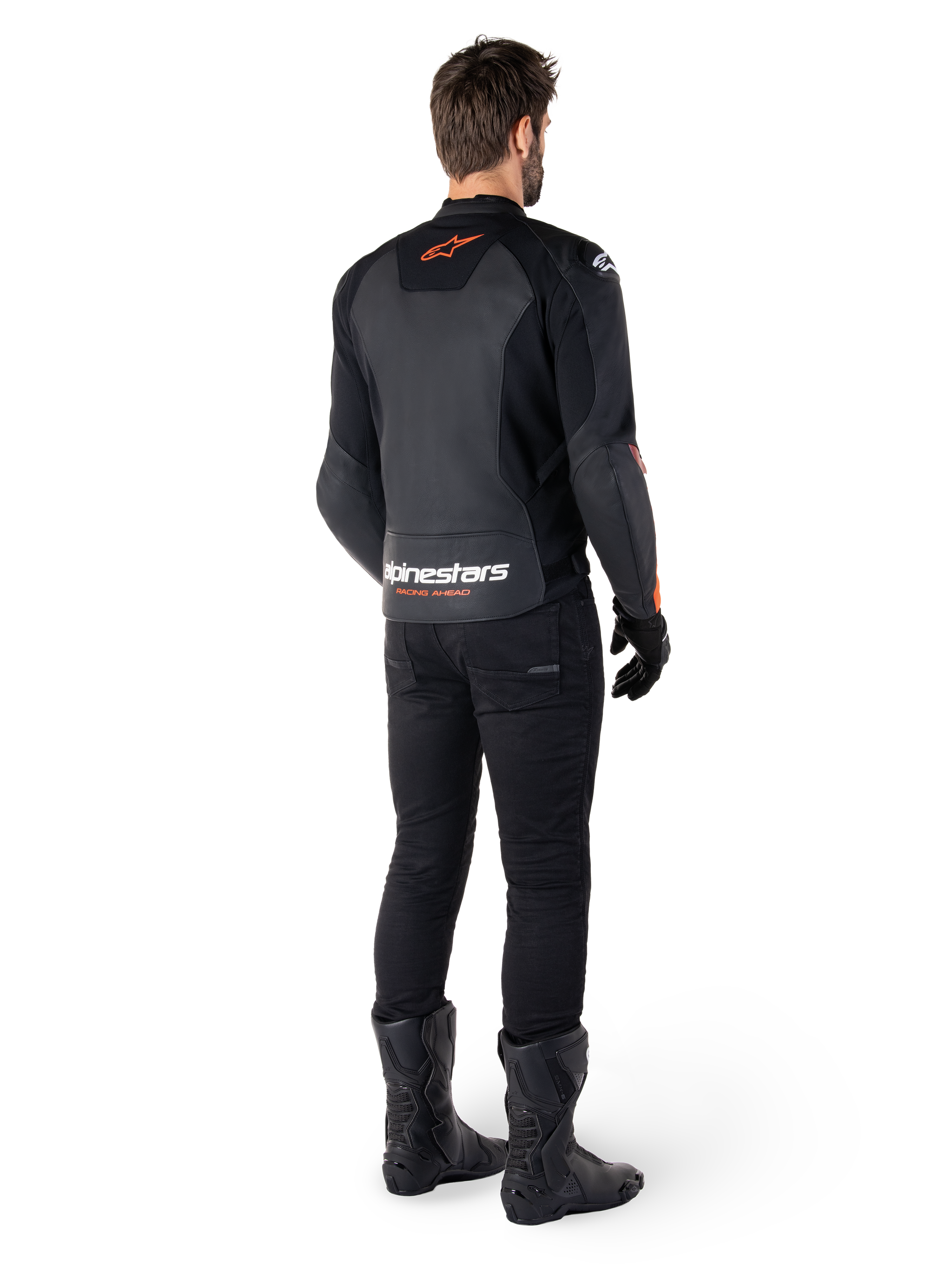 Giacca in pelle Alpinestars Faster V3, giacca da moto sportiva, nero e rosso fluo, vista posteriore indossata con pantaloni neri e stivali neri, con scritta 'alpinestars RACING AHEAD' sulla parte inferiore della schiena e un piccolo logo a stella rosso, struttura in pelle dal taglio sportivo