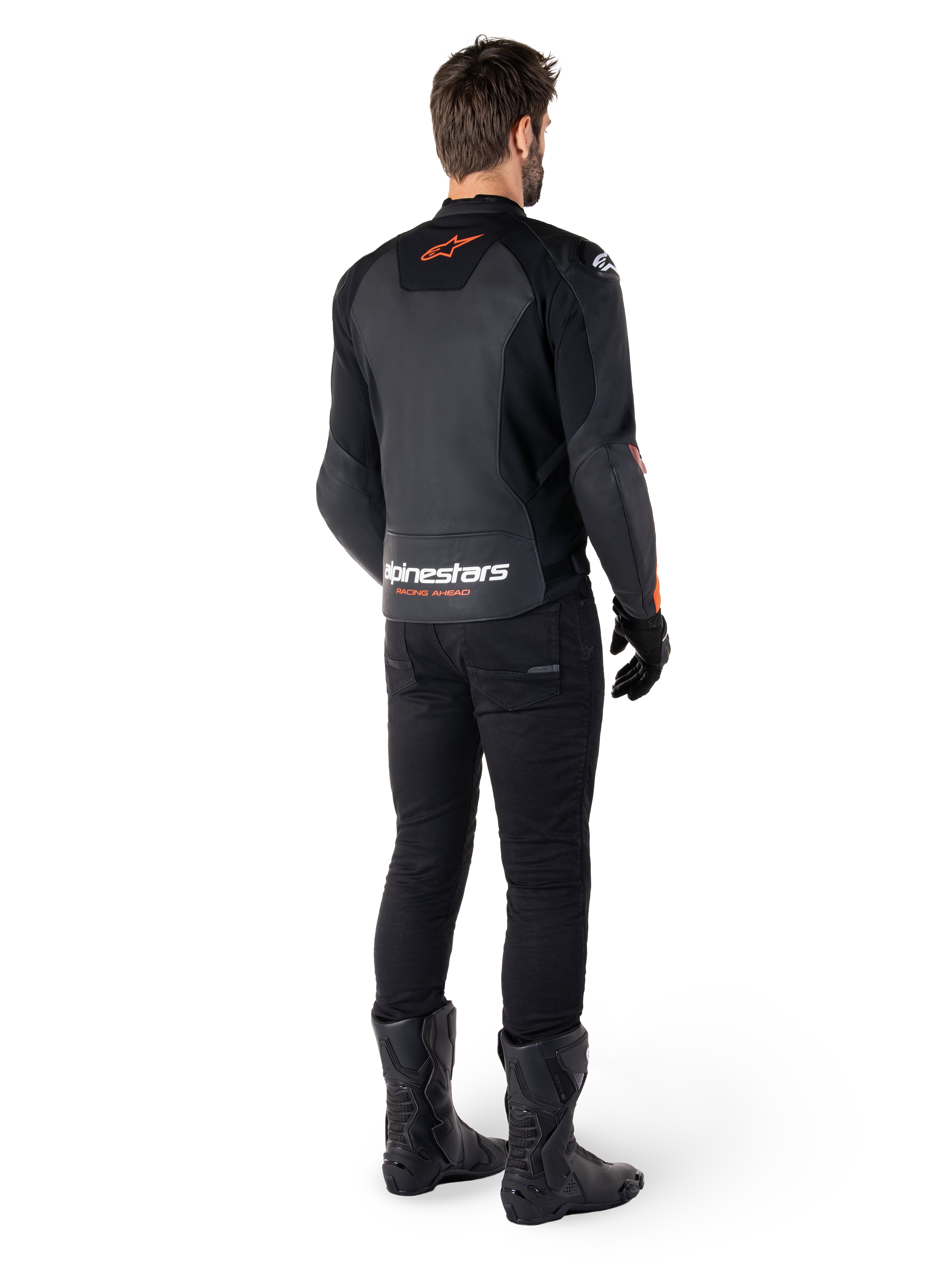 Giacca in pelle Alpinestars Faster V3, giacca da moto sportiva, nero e rosso fluo, vista posteriore indossata con pantaloni neri e stivali neri, con scritta 'alpinestars RACING AHEAD' sulla parte inferiore della schiena e un piccolo logo a stella rosso, struttura in pelle dal taglio sportivo