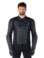 Giacca in pelle Alpinestars Faster V3, giacca da moto nera, pelle premium con pannelli elasticizzati HRSF, vestibilità sportiva, spalle rinforzate con protezioni, indossata con guanti neri, equipaggiamento professionale per la guida su strada