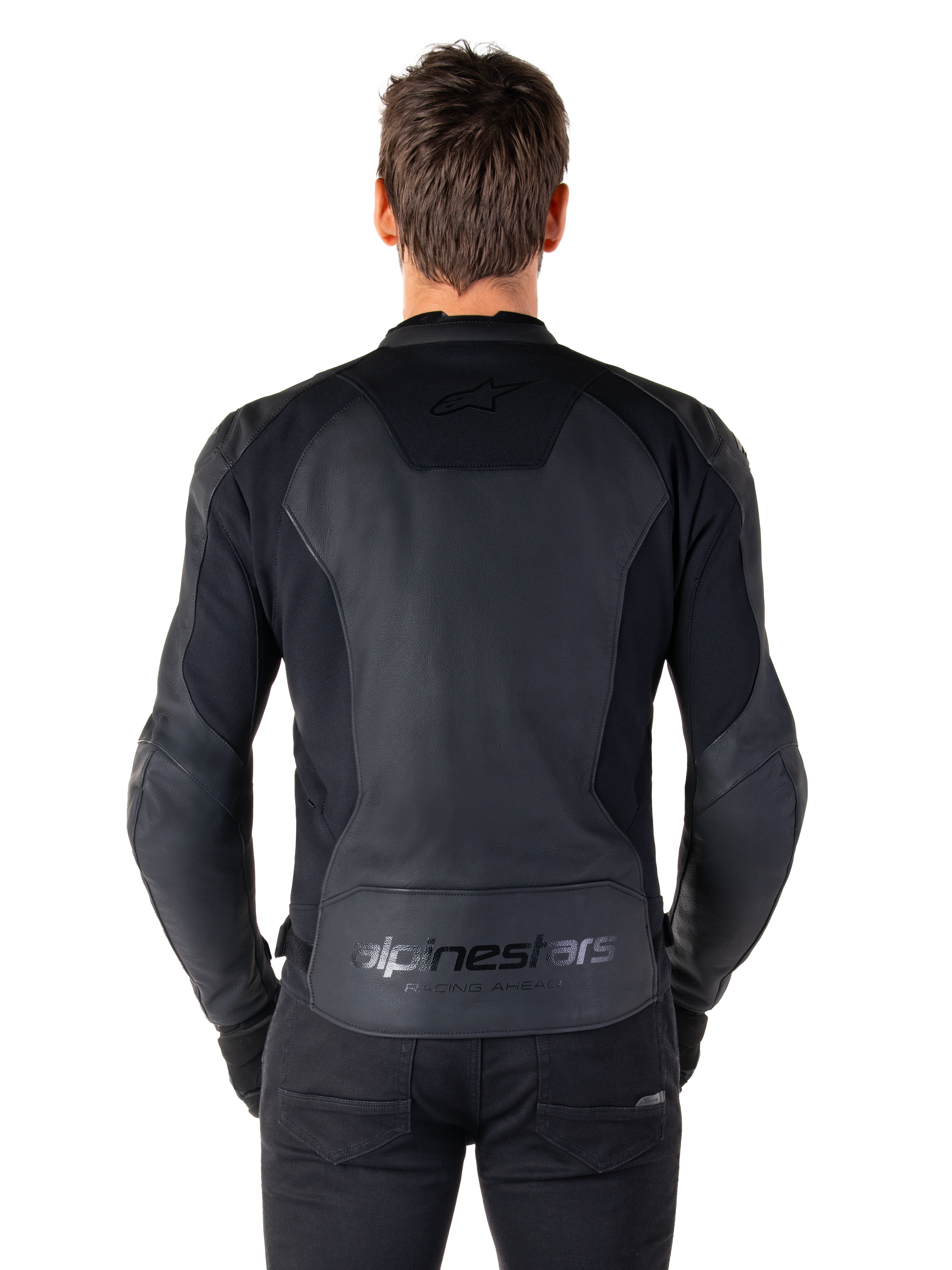 Vista posteriore di un uomo che indossa la giacca in pelle Alpinestars Faster V3 in Black Black, con pannelli in pelle premium e inserti elasticizzati flessibili, loghi discreti 'alpinestars' e 'RACING AHEAD' sulla parte bassa della schiena, vestibilità sportiva per la guida in moto.
