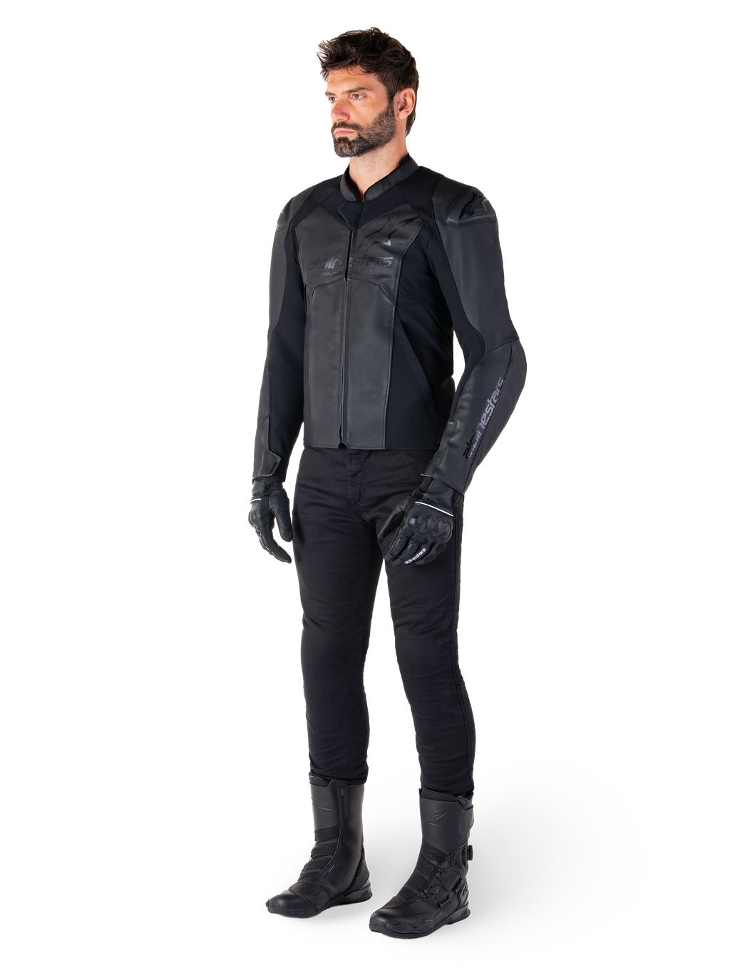 Giacca in pelle Alpinestars Faster V3, Nero, indossata con pantaloni, guanti e stivali neri, caratterizzata da una struttura in pelle tecnica con pannelli elasticizzati HRSF, protezioni per le spalle DFS GP Lite integrate e una silhouette sportiva raffinata.