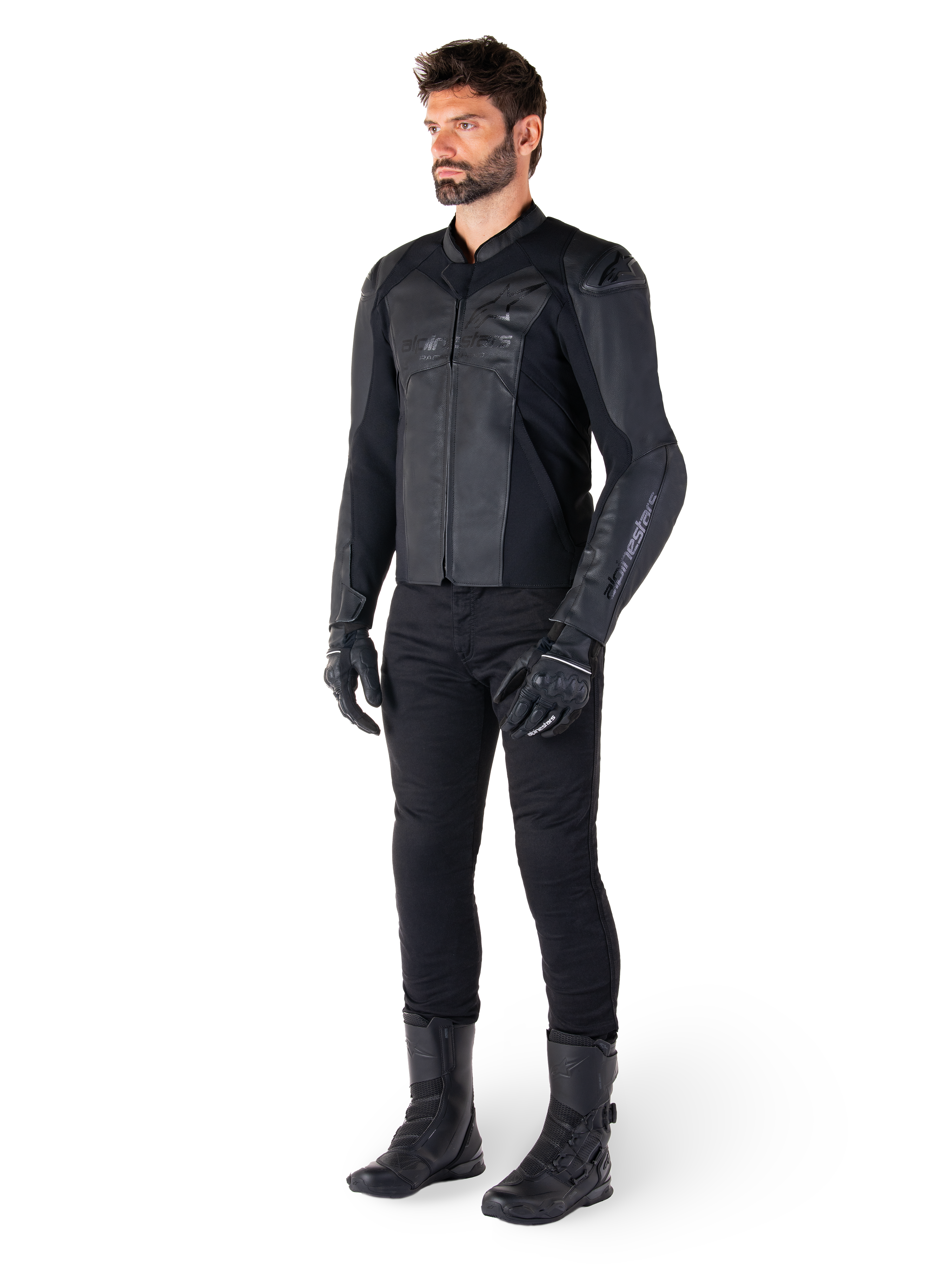 Giacca in pelle Alpinestars Faster V3, Nero, indossata con pantaloni, guanti e stivali neri, caratterizzata da una struttura in pelle tecnica con pannelli elasticizzati HRSF, protezioni per le spalle DFS GP Lite integrate e una silhouette sportiva raffinata.