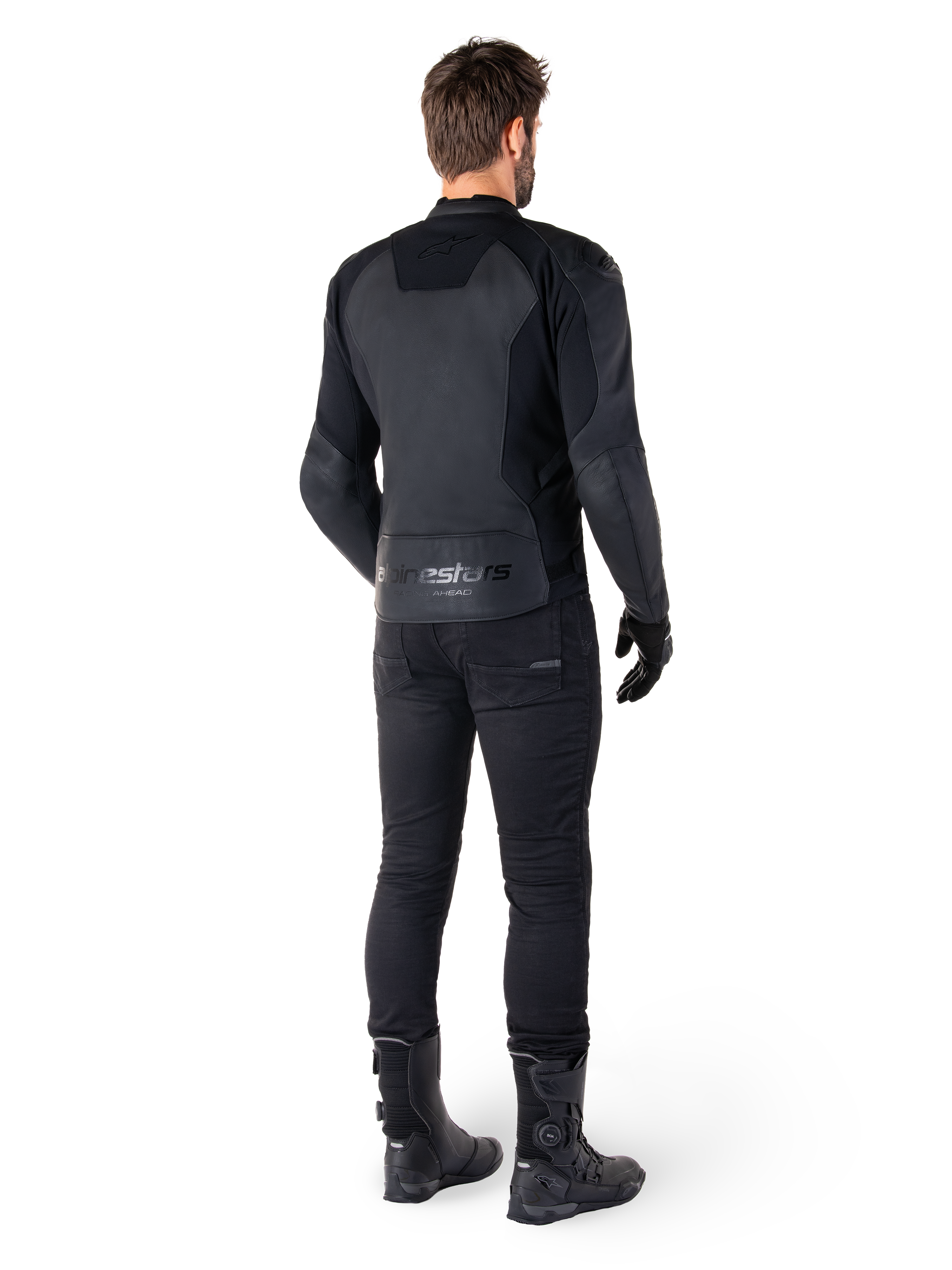 Alpinestars Faster V3 Leather Jacket, giacca in pelle da moto, nero, vista posteriore su un pilota, con pannelli in pelle pregiata e marchio Alpinestars in rilievo, abbinata a pantaloni e stivali da moto neri per un look sportivo completo.