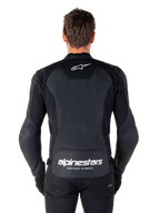 Giacca in pelle Alpinestars Faster V3, giacca da moto sportiva, nero con loghi bianchi, vista posteriore indossata da un modello, con logo Alpinestars sulla parte superiore della schiena e scritta 'RACING AHEAD' sulla parte inferiore, costruzione in pelle premium con pannelli elasticizzati ergonomici.