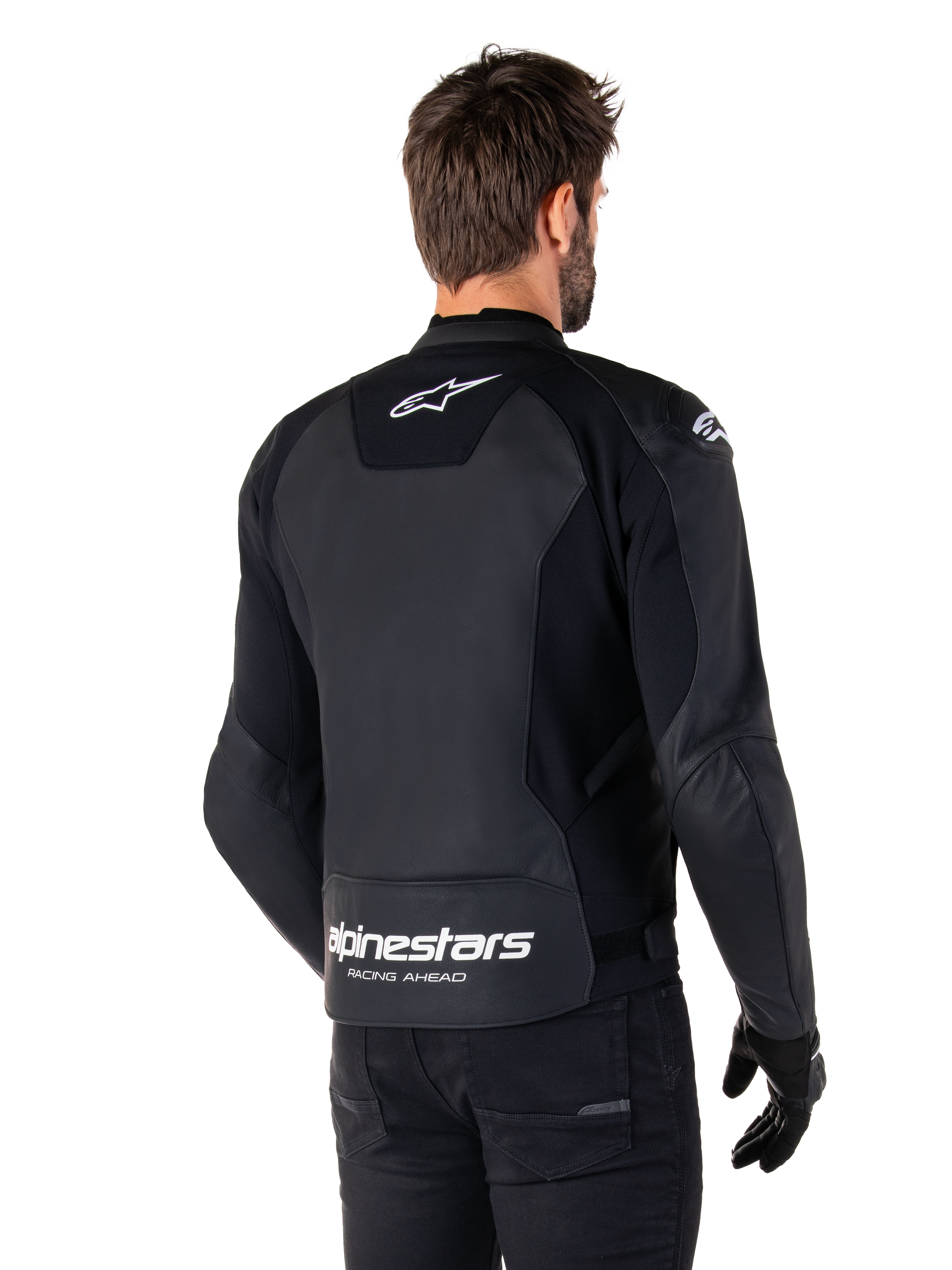 Giacca in pelle Alpinestars Faster V3, nero e bianco, vista posteriore su un pilota, con logo a stella bianco sulla parte superiore della schiena e grande marchio Alpinestars con "Racing Ahead" sulla parte inferiore del retro, retro allungato per una maggiore copertura durante la guida, costruzione in pelle sportiva premium