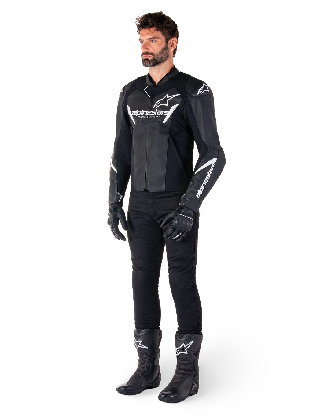 Modello che indossa la giacca in pelle Alpinestars Faster V3, giacca da moto sportiva, nero e bianco, abbinata a pantaloni, guanti e stivali da moto neri, con branding e loghi bianchi, silhouette sportiva per corse su strada