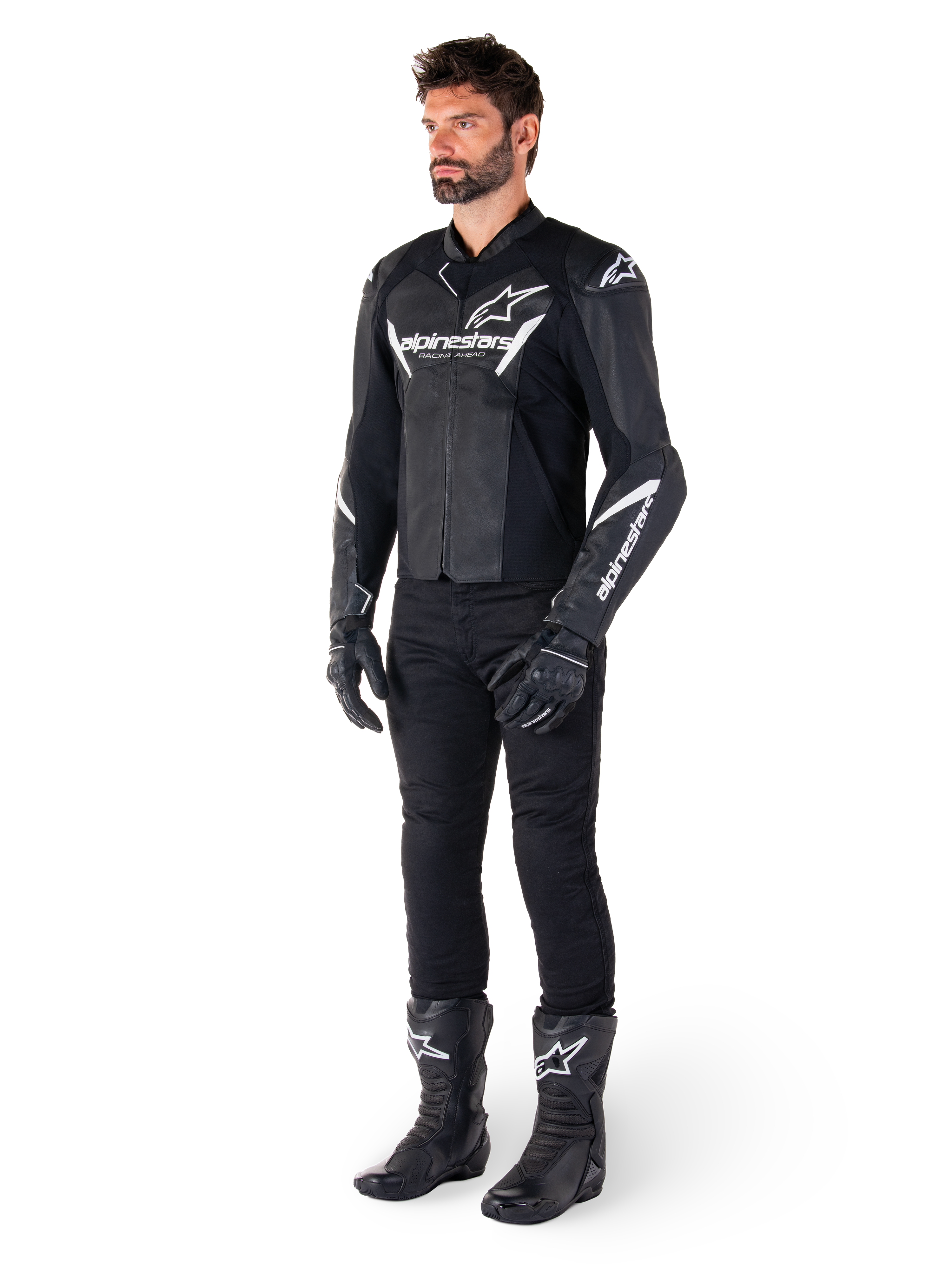 Modello che indossa la giacca in pelle Alpinestars Faster V3, giacca da moto sportiva, nero e bianco, abbinata a pantaloni, guanti e stivali da moto neri, con branding e loghi bianchi, silhouette sportiva per corse su strada