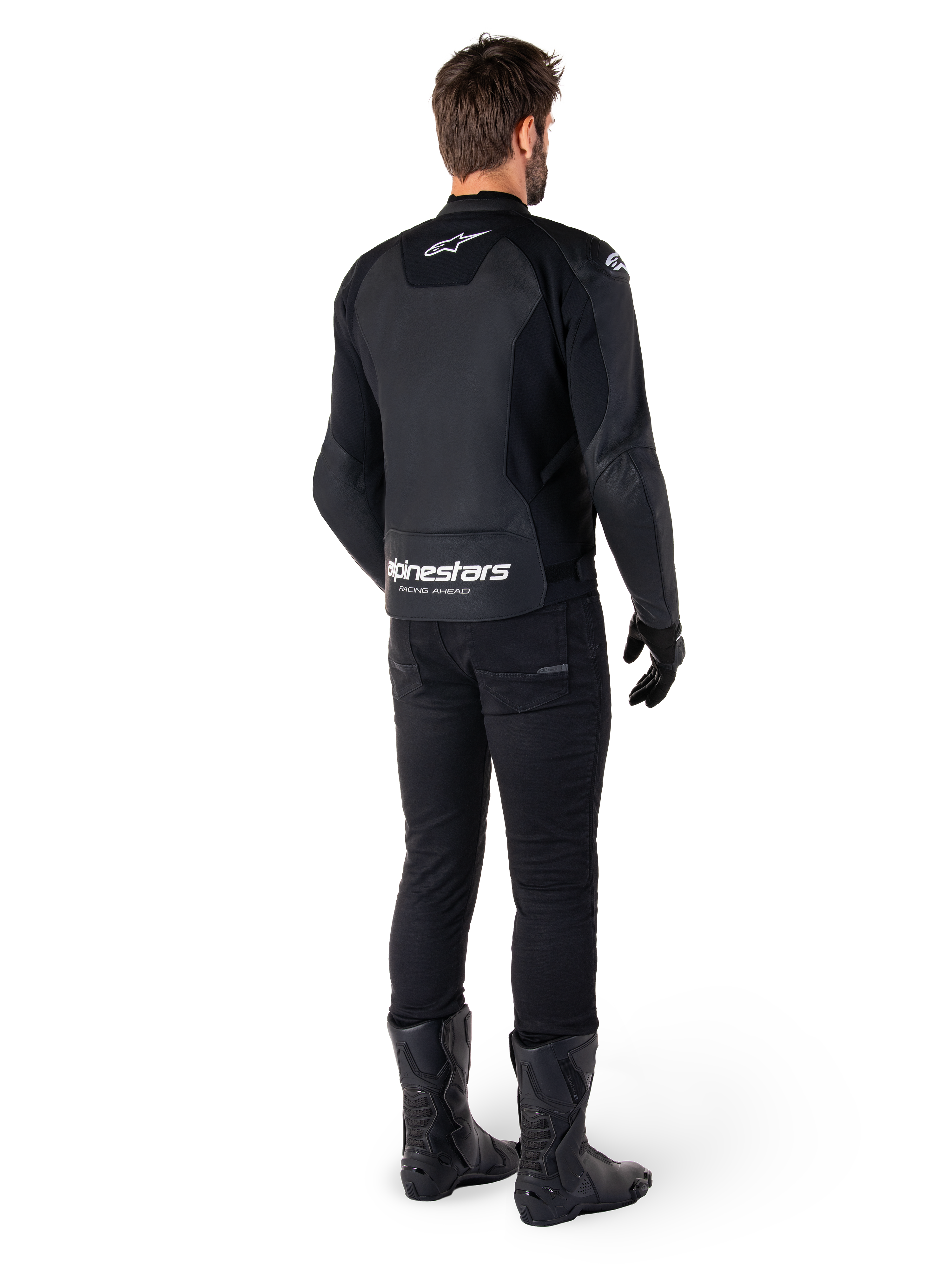 Giacca in pelle Alpinestars Faster V3, vista posteriore, nero e bianco, con marchio 'alpinestars RACING AHEAD' sulla parte bassa della schiena, indossata con pantaloni e stivali da moto neri, giacca da moto in pelle di derivazione sportiva con pannelli elasticizzati