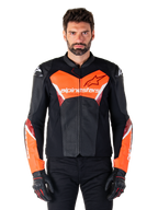 Alpinestars Faster V3 Airflow Leather Jacket, giacca da moto sportiva, nero e rosso fluo, struttura in pelle traforata con dettagli bianchi e rossi, indossata con guanti neri, abbigliamento tecnico per guida su strada