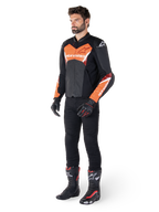Alpinestars Faster V3 Airflow Leather Jacket, giacca in pelle, nero e rosso fluo, indossata da un modello con pantaloni da moto neri, guanti e stivali da corsa, con pelle traforata e silhouette sportiva.