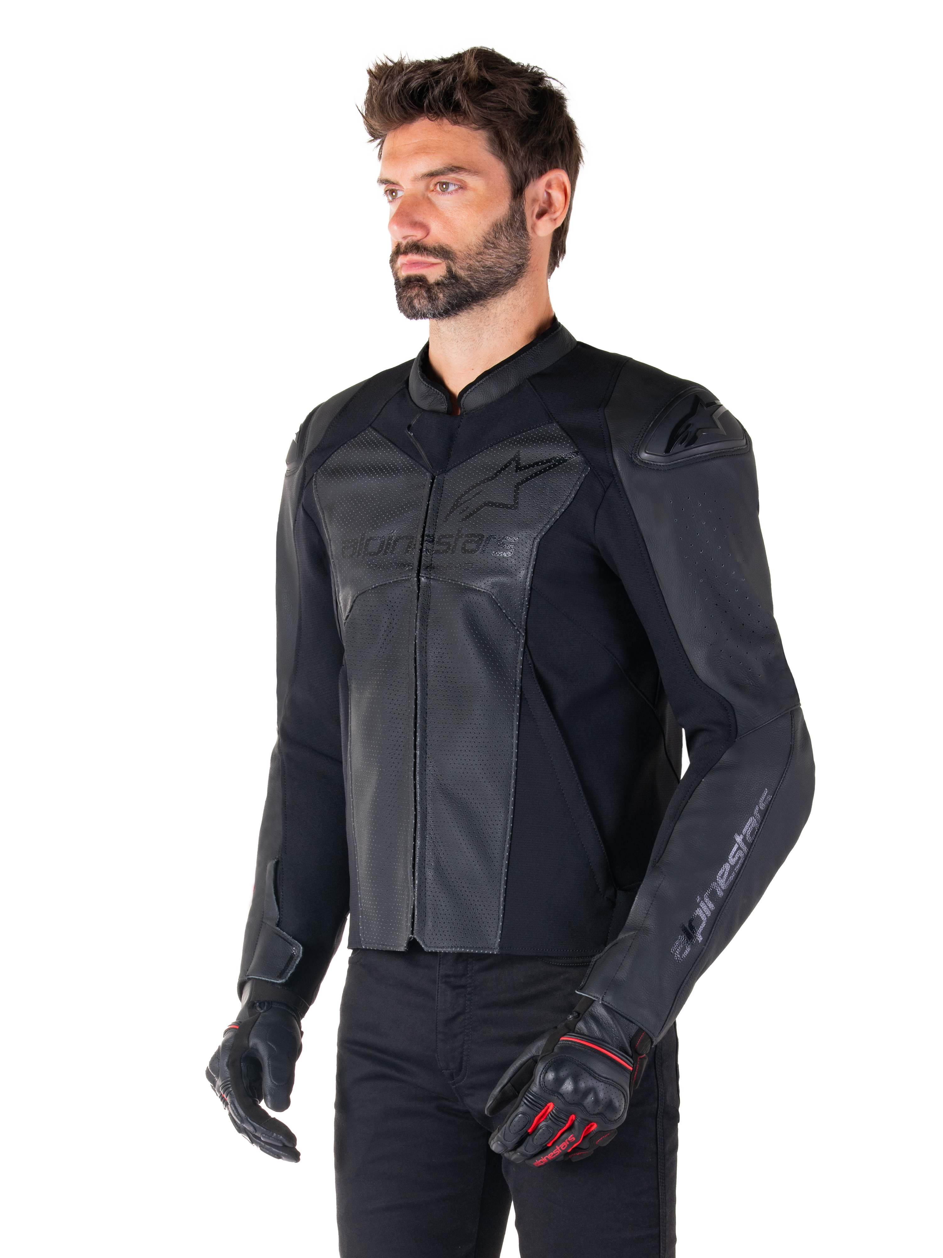 Modello che indossa la giacca in pelle Alpinestars Faster V3 Airflow in Black Black, giacca da moto sportiva con pelle traforata e pannelli elasticizzati, abbinata a pantaloni neri e guanti neri con accenti rossi, stile raffinato di derivazione racing